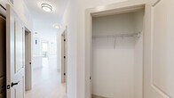 Located at 19 Harnett St in Wilmington, NC, this thoughtfully designed one-bedroom, two-bathroom residence offers a clean, modern aesthetic with a bright and airy atmosphere throughout. The open-concept kitchen and living area serves as the heart of the home, anchored by a sleek island with an undermount sink and light quartz countertops. The kitchen is outfitted with white shaker cabinetry, matte black hardware, stainless steel appliances, subway tile backsplash, and stylish pendant lighting — all set atop light-toned hardwood flooring that flows seamlessly through the main living spaces. Large windows flood the area with natural light and offer views of the surrounding Wilmington cityscape, while a door provides access to an outdoor balcony. The spacious bedroom features plush carpeting, a ceiling fan, and generous windows that continue the home's bright character. A well-appointed walk-in closet with wire shelving provides ample storage. The primary bathroom impresses with a dual-sink vanity, white cabinetry with matte black fixtures, a large mirror, and a glass-enclosed walk-in shower. A dedicated hallway closet adds further storage convenience. Clean white walls, recessed lighting, and consistent modern finishes create a cohesive, polished living environment throughout.