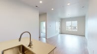 Located at 2255 E Fairview Ave in Meridian, Idaho, this single-floor unit showcases a clean, modern design with a neutral palette and thoughtful layout. The open-concept living and kitchen area forms the heart of the space, where light wood-tone laminate flooring extends throughout, complementing the crisp white walls and recessed lighting overhead. Large windows in the living area flood the space with natural light and offer views of the surrounding Meridian neighborhood.

The kitchen is well-appointed with light wood cabinetry extending to the ceiling, stainless steel Whirlpool appliances including a refrigerator, electric range, and over-the-range microwave, and a vertical tile backsplash. A central island with an undermount sink and light-toned countertop provides additional workspace and casual dining potential.

Bedrooms feature plush carpet flooring and generous windows with neighborhood views. Closet space is provided via sliding-door closets with built-in hanging rods. The primary bathroom includes a dual-sink vanity with light wood cabinetry, taupe countertops, and a large mirror with modern sconce lighting. A secondary bathroom offers a full tub-shower combination, single vanity, and wood-tone flooring. A door in the living area provides direct outdoor access.