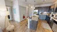Located at 1160 Montgomery Dr in Allen, TX, this thoughtfully designed single-floor residence offers a cohesive blend of modern finishes and functional living spaces. The open-concept kitchen is a standout, showcasing rich dark gray cabinetry, granite countertops, a subway tile backsplash, and a full suite of stainless steel appliances. A spacious island with pendant lighting provides additional prep space and casual seating, flowing seamlessly into the dining and living areas. Light wood-style flooring runs throughout the main living spaces, enhancing the bright, airy atmosphere.

The living room is generously proportioned, featuring a ceiling fan, large windows, and a glass door that opens to a private balcony with exterior views — flooding the room with natural light. Two well-sized bedrooms each feature plush carpeting, ceiling fans, and ample natural light from large windows. Each bedroom benefits from its own walk-in closet, offering excellent storage.

The bathrooms are finished with granite-topped dark vanities and wood-style flooring. The primary bath includes a soaking tub and shower combination, while the secondary bath features a walk-in shower. The overall design is clean, contemporary, and cohesive throughout.