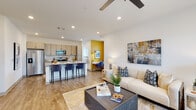 This well-designed single-floor residence offers a thoughtfully arranged open-concept layout that seamlessly connects the living, dining, and kitchen areas. The living room is bright and inviting, featuring large windows that allow abundant natural light, wood-look flooring, a ceiling fan, and direct access to the entry. A bold yellow accent wall defines a dedicated workspace nook, adding a vibrant pop of color and a functional area for productivity.

The kitchen is a standout feature, equipped with stainless steel appliances including a French door refrigerator, microwave, and range, complemented by light wood cabinetry, a subway tile backsplash, and granite countertops. A spacious island with bar seating provides additional prep and dining space.

The bedroom is a comfortable retreat, highlighted by a large window with views of the surrounding neighborhood, allowing plenty of natural light to fill the room. The bathroom features a glass-enclosed walk-in shower and granite vanity countertop, maintaining the modern aesthetic found throughout the space.

A practical mudroom area with wall hooks and a bench seat sits adjacent to an in-unit laundry station equipped with a full-size washer. Wood-look flooring runs throughout, tying the space together with a clean, contemporary feel.
