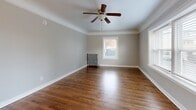 Located at 518 S 7th St in Tacoma, WA, this one-bedroom, one-bathroom unit offers a well-organized single-floor layout that makes efficient use of its intimate footprint. Rich hardwood floors flow consistently throughout the space, lending warmth and character to every room. Crown molding adds a classic architectural touch that elevates the overall aesthetic.

The living room is a bright and open area featuring a ceiling fan with a light fixture, crisp white baseboards, and a large window that invites natural light and views of the surrounding neighborhood. A central hallway connects the rooms with ease, accented by wall-mounted sconce lighting and a built-in mirror that enhances the sense of space.

The bedroom is a cozy yet functional room with hardwood floors, a window for natural light, and a vintage cast-iron radiator that adds both charm and warmth. Built-in shelving provides convenient storage. The kitchen is efficiently designed with white cabinetry, butcher block countertops, and a classic coil-top electric range. The dining room provides a dedicated space for meals adjacent to the kitchen.

The bathroom is clean and bright, featuring a full soaking tub with a marble-patterned surround, chrome fixtures, a single vanity with a sink, and a mirrored medicine cabinet above.