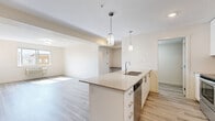 Located at 1469 K.L.O Rd in Kelowna, BC, this well-appointed three-bedroom, one-bathroom unit offers a thoughtfully designed single-floor layout with modern finishes throughout. Light grey vinyl plank flooring runs seamlessly across every room, creating a clean and cohesive aesthetic.

The open-concept kitchen and living area serves as the heart of the home. The kitchen is highlighted by a large peninsula with a quartz countertop, undermount sink, and stylish pendant lighting. White cabinetry reaches toward the ceiling, providing ample storage, while a full suite of stainless steel appliances — including a refrigerator, stove, and over-the-range microwave — complete the contemporary look. A grey subway tile backsplash adds a refined finishing touch.

Each of the three bedrooms is bright and comfortably sized, featuring windows that bring in natural light and views of the surrounding neighbourhood. Ceiling fans and baseboard heaters ensure year-round comfort. Two closets provide convenient storage options.

The bathroom is clean and functional, featuring a quartz-topped vanity with modern hardware and durable flooring. A dedicated laundry room with in-unit washer and dryer adds everyday convenience. The space also includes a private entry door, making it feel welcoming and self-contained.