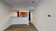 This single-floor residence showcases a thoughtfully designed open-concept layout that connects the living areas to a pass-through kitchen. The living space is particularly notable for its vaulted, angled ceiling accented by a ceiling fan, which adds a sense of height and openness. A sliding glass door floods the area with natural light and provides access to an outdoor balcony. Wood-style plank flooring runs throughout the entire unit, offering a cohesive and contemporary aesthetic.

The kitchen is efficiently laid out with warm-toned cabinetry, granite-style countertops, and black appliances including a range, dishwasher, and refrigerator. A raised breakfast bar separates the kitchen from the living area, creating a functional and social space.

The bedrooms are well-proportioned, each equipped with ceiling fans and generous closet storage. The primary bedroom features dual sliding closets and an adjoining bathroom access. A secondary bedroom benefits from its own window, allowing natural light to filter in. The bathroom is clean and functional, featuring a single vanity with a large mirror.

Throughout the unit, white walls and textured ceilings complement the warm flooring, creating a bright and inviting atmosphere.