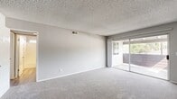 Located at 10522 Santa Gertrudes Ave in Whittier, CA, this single-floor, three-bedroom, two-bathroom unit offers a well-organized layout designed for comfortable everyday living. The living area is carpeted and filled with natural light, thanks to a full-width sliding glass door that opens to an outdoor space, offering pleasant views of surrounding greenery. A textured ceiling adds classic character throughout the main living spaces.

The kitchen is appointed with rich dark-wood cabinetry lining both walls, light stone countertops, a stainless steel sink, and stainless appliances including a gas range and refrigerator. Wood-look vinyl flooring runs through the kitchen and bathrooms, providing a clean, durable finish.

The generously sized primary bedroom features mirrored sliding closet doors that enhance the sense of space, along with soft carpet flooring. Additional bedrooms are also carpeted and include mirrored closet doors and windows that bring in natural light.

Both bathrooms are finished with dark wood vanities and stone countertops. The first bathroom features a sliding glass-enclosed shower, while the second offers a full tub-shower combination with tiled surround and a window for natural ventilation. Two hallways connect the rooms efficiently, completing a practical and well-appointed floor plan.