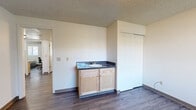 Located at 1555 NE Merman Dr in Pullman, Washington, this three-bedroom, one-bathroom unit offers a practical and well-organized single-floor layout. Wood-look flooring runs throughout the entire space, providing a cohesive and easy-to-maintain finish, while textured ceilings add a classic touch to each room.

The living room greets you at the entrance with a dark-paneled front door and a window that allows natural light to fill the open area. The kitchen is efficiently designed in a U-shaped configuration, featuring light maple cabinetry, a stainless steel dishwasher, a full-size refrigerator, and a window-facing sink. A stacked washer and dryer unit is conveniently integrated into the kitchen space.

Each bedroom is well-proportioned and features its own closet. The spacious primary bedroom stands out with a built-in vanity, sink with light maple cabinetry, a large mirror with Hollywood-style lighting, and a sliding closet. The additional bedrooms are bright, with windows and ample floor space suitable for a bed and a study area.

The shared bathroom is clean and functional, featuring a full soaking tub with white subway tile surround, a towel bar, and matching wood-look flooring. A connecting hallway ties all rooms together, making for an efficient and livable floor plan.
