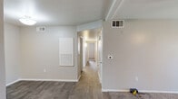 This single-floor residence offers a clean, functional layout with a neutral color palette and thoughtful design details throughout. The main living area features wood-look flooring, a ceiling fan, and a sliding glass door that invites natural light and provides access to an outdoor space. The open feel continues through a central hallway connecting the key areas of the home.

The kitchen is a standout feature, showcasing modern two-tone cabinetry, a subway tile backsplash, white quartz-style countertops, a peninsula with bar-style seating, and black appliances including a gas range, microwave, refrigerator, and dishwasher. Wood-look tile flooring completes the contemporary aesthetic.

The bedrooms are finished with plush carpeting and ceiling fans, providing a comfortable and cozy atmosphere. Additional rooms with wood-look flooring offer flexible use as an office or secondary living space, complete with built-in HVAC access panels.

The bathrooms are updated and well-appointed. One features a full tub and shower combo with a curved curtain rod, wood-look tile flooring, and a dark-toned vanity with a white countertop. A second bathroom mirrors this style with a single vanity, mirrored medicine cabinet, and a clean, modern finish. Multiple HVAC vents throughout ensure consistent climate control across the entire residence.