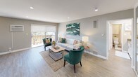 This single-floor residence offers a thoughtfully designed layout with modern finishes and a cohesive neutral color palette. The galley-style kitchen is a functional highlight, featuring stainless steel appliances including a gas range, microwave, and refrigerator, complemented by sleek white cabinetry, gray quartz countertops, a double-basin sink, and a marble-style tile backsplash. Light wood-look flooring runs throughout the main living areas, enhancing the bright and airy feel of the space.

The open living area is generously proportioned, with recessed lighting and a sliding glass door that brings in natural light and provides access to an outdoor balcony. A dedicated dining nook accommodates a full dining set and includes windows that add additional natural light to the space.

The bedroom is finished with soft carpeting and features full-length mirrored sliding closet doors that amplify the sense of space. An en-suite bathroom is accessible directly from the bedroom, appointed with white cabinetry, a vanity mirror with integrated lighting, and a clean tub-shower combination with white tile surround. Throughout the residence, warm gray walls, recessed lighting, and clean white trim create a polished and move-in-ready environment.