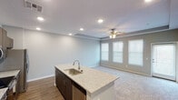 Located on S Wren Dr in Gilbert, Arizona, this single-story residence showcases a modern, open-concept design with thoughtful finishes throughout. The kitchen serves as a central hub, anchored by a large island with a granite countertop and undermount sink. Dark espresso cabinetry lines the walls, complemented by a subway tile backsplash, stainless steel appliances including a refrigerator with ice maker, electric range, and built-in microwave. Wood-style flooring runs through the kitchen and transitions to plush carpet in the living and bedroom areas.

The living space is generously proportioned, featuring a tray ceiling with a ceiling fan and multiple windows dressed with blinds that allow ample natural light. The neutral gray tones of the walls create a calm, cohesive atmosphere throughout. Bedrooms continue the tray ceiling detail and carpeted floors, offering comfortable, well-lit spaces with ceiling fans.

The primary bathroom is well-appointed with a dual-sink granite vanity, dark cabinetry, modern light fixtures, framed mirrors, and direct access to an adjoining carpeted area. A dedicated laundry alcove houses a full-size top-load washer and dryer with an overhead shelf, adding everyday convenience to this well-designed Gilbert home.
