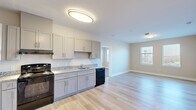 This single-floor residence offers a thoughtfully designed layout with 2 bedrooms, 3 bathrooms, a kitchen, living room, and a dedicated closet. The kitchen serves as a functional centerpiece, featuring gray shaker-style cabinetry, granite-look countertops, and black appliances including a range, refrigerator, and dishwasher. Light hardwood flooring runs throughout the main living and kitchen areas, contributing to a clean, contemporary aesthetic. The open layout allows the kitchen to flow naturally into the living area, which benefits from a window that brings in natural light.

The spacious primary bedroom is finished with plush carpeting and features two windows that allow ample daylight. The second bedroom similarly offers carpeted flooring, two windows with outdoor views, and neutral wall tones. The bathrooms are finished with tile flooring and include tub-shower combinations with white subway tile surrounds and built-in niches. The entry area features light hardwood flooring, flush-mount lighting, and climate control access. Neutral wall tones and white trim are consistent throughout, giving the space a cohesive, move-in-ready feel.
