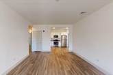 Located at 5300 Westbrook Blvd in East Islip, New York, this single-floor unit offers a clean, contemporary design with a bright and open layout. The main living area is expansive and airy, featuring smooth wood-look flooring and crisp white walls that enhance the sense of space and light throughout. The open-plan design connects the living area seamlessly to the kitchen, which is well-appointed with white shaker-style cabinetry, dark countertops, and a full suite of stainless steel appliances including a refrigerator, range, and microwave. A louvered door nearby provides access to a built-in closet with shelving, adding practical storage. Natural light enters through windows fitted with blinds, contributing to the unit's welcoming ambiance. The bedroom is generously sized with plush carpeting underfoot and a window that frames outdoor views. The bathroom is finished in a modern, understated style with large-format gray tile flooring, a white vanity with ample cabinet storage, a round mirror, and clean chrome fixtures. Throughout the unit, the consistent use of white tones, quality finishes, and thoughtful layout creates a comfortable and functional living environment.