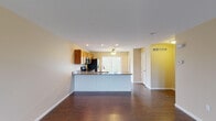 This 3-floor home offers a well-designed layout with consistent finishes throughout. The main living area features an open-concept floor plan, where the kitchen flows seamlessly into the living space. Dark hardwood flooring runs throughout, complemented by neutral warm-toned walls and white trim. The kitchen is equipped with stainless steel appliances, including a range, over-the-range microwave, and refrigerator with ice and water dispenser. Warm wood cabinetry provides ample storage, while dark granite countertops extend across both the perimeter and a central peninsula with an integrated sink — ideal for casual dining or meal prep. Recessed lighting and a ceiling fan keep the space bright and comfortable. A spacious living room with its own ceiling fan and large windows allows natural light to fill the room. A sliding glass door in one of the rooms opens directly onto a covered deck, offering views of surrounding greenery. The bathrooms are finished with stone-tile flooring, dark wood vanities with granite-style countertops, and full tub-shower combinations. A convenient half-bath with hardwood flooring and a large vanity mirror serves the main level. Throughout, ceiling fans, HVAC vents, and recessed lighting reflect a thoughtfully functional design.