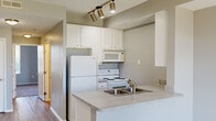 Located at 10302 Desmond Pl in Perrysburg, Ohio, this single-floor, one-bedroom, one-bathroom unit offers a practical and well-organized layout across a compact but efficient footprint. Neutral gray tones and consistent finishes create a cohesive aesthetic throughout.

The kitchen is a standout feature, designed with white cabinetry extending to the ceiling for ample storage, granite-style laminate countertops, a stainless steel double-basin sink, and a peninsula that opens to the living area. Track lighting overhead provides focused illumination, while white appliances including a refrigerator, electric range, and over-the-range microwave complete the space. Light wood-style flooring runs through the kitchen and living area, adding warmth.

The living room benefits from large patio doors with transom windows above, flooding the space with natural light and providing views of the surrounding neighborhood. The bedroom is a comfortable size, featuring plush carpet, two windows with exterior views, and soft neutral walls.

The bathroom includes a full tub/shower combo, a white vanity with granite-style countertop, and wood-look flooring. A dedicated laundry area accommodates a full-size washer and dryer with wire shelving above for additional storage. A hallway connects the spaces efficiently, rounding out this well-appointed unit.