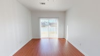 This single-floor, 2-bedroom, 2-bathroom unit features a clean, functional layout with consistent finishes throughout. The living area is finished with warm wood-look flooring and receives generous natural light through a sliding glass door fitted with vertical blinds, which opens to an outdoor view of the surrounding area.

The kitchen is well-equipped with warm-toned wooden cabinetry, granite-style countertops, and black appliances including a range, microwave, and refrigerator. A peninsula counter provides additional workspace and separation between the kitchen and living area. Light tile flooring runs throughout the kitchen, which also includes a utility panel and convenient access to a walk-in closet or storage area nearby.

Both bedrooms are carpeted and feature large windows that allow ample natural light, along with ceiling fans for added comfort. The rooms offer a quiet, neutral atmosphere suitable for a range of furnishing arrangements.

The two bathrooms are similarly appointed, each featuring a tub/shower combination, tile flooring, and rich wooden cabinetry for overhead storage. One bathroom also includes a vanity with an integrated sink and an oval mirror, providing additional functionality.

Overall, the unit presents a cohesive, neutral aesthetic with practical finishes throughout.