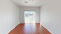 This single-floor, 2-bedroom, 2-bathroom unit features a clean, functional layout with consistent finishes throughout. The living area is finished with warm wood-look flooring and receives generous natural light through a sliding glass door fitted with vertical blinds, which opens to an outdoor view of the surrounding area.

The kitchen is well-equipped with warm-toned wooden cabinetry, granite-style countertops, and black appliances including a range, microwave, and refrigerator. A peninsula counter provides additional workspace and separation between the kitchen and living area. Light tile flooring runs throughout the kitchen, which also includes a utility panel and convenient access to a walk-in closet or storage area nearby.

Both bedrooms are carpeted and feature large windows that allow ample natural light, along with ceiling fans for added comfort. The rooms offer a quiet, neutral atmosphere suitable for a range of furnishing arrangements.

The two bathrooms are similarly appointed, each featuring a tub/shower combination, tile flooring, and rich wooden cabinetry for overhead storage. One bathroom also includes a vanity with an integrated sink and an oval mirror, providing additional functionality.

Overall, the unit presents a cohesive, neutral aesthetic with practical finishes throughout.