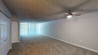 This single-floor residence features a thoughtful layout encompassing two bedrooms, two bathrooms, a kitchen, a closet, and a dedicated entrance. The living area is generously sized, finished with plush wall-to-wall carpet and fitted with a ceiling fan with integrated lighting. A wide bank of vertical blinds allows abundant natural light to fill the room, creating a bright and open atmosphere.

The kitchen is equipped with white cabinetry, a gas range with overhead ventilation, and light wood-look flooring that extends throughout the cooking space. The countertops feature a speckled finish, and the cabinetry provides ample storage throughout.

The spacious primary bedroom offers comfortable proportions, its own access to a walk-in closet complete with dual hanging rods and built-in shelving. A second bedroom features neutral carpet, a large window with blinds for natural light, and a textured ceiling.

Both bathrooms are finished consistently, featuring speckled quartz-style countertops, large vanity mirrors with overhead lighting, wood-look tile flooring, and brushed nickel hardware and grab bars. One bathroom includes a full tub and shower combination with white tile surround. Throughout, the neutral color palette and clean finishes lend the space a cohesive and move-in-ready appeal.