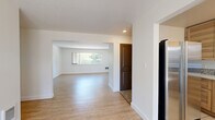 Located at 9008 NE Hassalo St in Portland, Oregon, this single-floor, three-bedroom, one-bathroom home offers a clean, modern aesthetic with a practical layout. Light hardwood-style flooring flows consistently throughout the living spaces, complementing the crisp white walls and creating a bright, cohesive feel.

The open living area is generously sized, benefiting from natural light through large windows that frame views of surrounding greenery. A sliding glass door adds additional light and outdoor access. The layout connects seamlessly to a hallway leading to the bedrooms and bathroom.

The kitchen features light natural wood cabinetry, stainless steel appliances including a range, over-the-range microwave, and dishwasher, paired with white quartz-style countertops and a mosaic tile backsplash. A window above the sink brings in natural light.

The primary bedroom is well-proportioned and includes dual dark-paneled closet doors, a wide window overlooking lush trees, and ample floor space. Additional bedrooms are similarly finished with light flooring and dark-accented doors, one featuring a built-in closet.

The bathroom is cleanly updated with large-format tile flooring, a tiled tub-shower combination, a dark-framed vanity with a stone-style countertop, open shelving, and a frosted window for privacy and light.