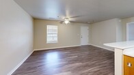 Located at 701 S Juniper St in Foley, Alabama, this single-floor, 3-bedroom, 3-bathroom unit offers a well-organized and functional layout. The open-concept kitchen and living room serve as the heart of the home, where warm honey-toned wood cabinetry pairs with a light-colored countertop peninsula that doubles as a breakfast bar. White appliances, including a refrigerator and electric range with overhead ventilation, keep the kitchen practical and clean. A chandelier pendant light anchors the dining area adjacent to the kitchen, adding a touch of elegance to the space. Wood-look flooring runs throughout the main living areas and bedrooms, providing a cohesive and easy-to-maintain finish. The spacious living room features a ceiling fan, neutral walls, and a window that brings in natural light, while a dedicated entry door adds convenience. Each of the three bedrooms is outfitted with ceiling fans and windows, creating bright, comfortable retreats. The bathrooms are simply appointed, featuring full tub-and-shower combinations, vanities, and wood-look flooring that ties in with the rest of the home. A hallway connects all rooms efficiently. The overall ambiance is clean, neutral, and move-in ready, offering a comfortable living environment in a quiet Foley neighborhood.