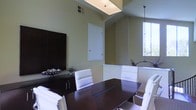 This single-floor professional office space is designed with a clean, contemporary aesthetic that promotes a polished and productive environment. The centerpiece of the space is a well-appointed conference room featuring a large, dark espresso-finished conference table surrounded by sleek white leather chairs, creating a striking contrast that exudes professionalism and style.

The room benefits from vaulted ceilings that enhance the sense of openness, while a skylight overhead floods the space with natural light, complementing the warm, neutral tones of the walls. A tall window along one side further amplifies the brightness, offering views of the surrounding greenery outside.

Architectural details include angled ceiling lines and a recessed accent wall with subtle textured wallcovering, adding depth and visual interest to the interior. A dark wood credenza along one wall provides functional storage while reinforcing the room's sophisticated color palette.

The overall ambiance is refined and professional, with thoughtful design choices that balance form and function. The interplay of natural light, elevated ceilings, and modern furnishings makes this an inviting and impressive space well-suited for meetings, presentations, or executive use.