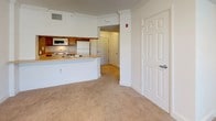 This single-floor, 1-bedroom, 1-bathroom unit in Concord offers a practical and comfortable layout designed for easy everyday living. The open-concept living and kitchen area serves as the heart of the home, where a curved breakfast bar counter seamlessly connects the kitchen to the living space. The kitchen is equipped with wood-toned cabinetry, a white appliance suite including a refrigerator, electric range, and over-the-range microwave, and a sink positioned along the bar for added convenience. Crown molding accents the living area, which features soft carpeting and a ceiling fan with light fixture, while windows fitted with blinds allow for natural light and privacy. The bedroom is a calm, carpeted retreat with a window that brings in ample natural light, clean white walls, and generous proportions suitable for various furniture arrangements. The full bathroom is finished with light tile flooring, warm oak cabinetry beneath a single-basin vanity with a white countertop, a large mirror with overhead lighting, a wall-mounted storage cabinet, and a toilet. The unit's neutral color palette and clean finishes create a bright, move-in-ready atmosphere throughout.