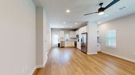 This two-story home in Fort Worth, TX offers a thoughtfully designed layout spread across two floors. The main level features an open-concept kitchen and living area with warm hardwood-style flooring, recessed lighting, and a ceiling fan. The kitchen is appointed with crisp white shaker cabinets, granite countertops, a subway tile backsplash, stainless steel appliances including a refrigerator, range, microwave, and dishwasher, plus a pantry for additional storage. A bright entryway with a staircase connects the main floor to the upper level. Also on the main floor is an office and a full bathroom featuring granite vanity countertops, white cabinetry, and matte black fixtures. Upstairs, two bedrooms are finished with plush carpet flooring and ceiling fans, each offering multiple windows with outdoor views that fill the rooms with natural light. The primary bedroom is a generous size with ample closet space. Two additional bathrooms on the upper level echo the home's consistent design language, including a full tub-shower combo with white subway tile and matte black hardware. Outside, a private backyard enclosed by modern horizontal wood fencing completes this well-appointed home.