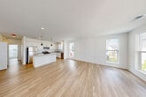 Located at 2501 Avant Ave in Ann Arbor, MI, this two-story home offers a clean, contemporary design across two well-appointed floors. The main level is anchored by a bright, open-concept kitchen and living area finished with light hardwood flooring throughout. The kitchen is a standout feature, showcasing white shaker cabinetry, granite countertops, a central island with pendant lighting, and a full suite of stainless steel appliances including a refrigerator, range, microwave, and dishwasher. Large windows fill the living area with natural light and offer views of the surrounding neighborhood. A sliding glass door provides access to an outdoor balcony. The entry level features a carpeted staircase leading upstairs, a convenient closet, and direct access to the exterior. Upstairs, two bedrooms are finished with plush carpeting and ample natural light — the primary bedroom is generously sized, while the second bedroom offers neighborhood views through tall windows. Two full bathrooms complete the upper floor, each featuring a soaking tub with shower, light tile flooring, and a bright window. The home's crisp white walls and modern finishes create a clean, cohesive aesthetic throughout.