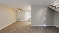 This two-story residence offers a well-organized layout designed for comfortable everyday living. The main level features an open living area finished with light-toned wood-look flooring, neutral beige walls, and a ceiling fan overhead. A sliding glass door floods the space with natural light and provides access to an outdoor area, while a carpeted staircase with a railing leads to the upper floor. The kitchen is outfitted with white cabinetry, marble-style countertops, a gas range with overhead ventilation, and ample upper and lower cabinet storage. Two full bathrooms are present throughout the home, each featuring a tub-shower combination, wood-look flooring, and clean white fixtures. The bedrooms are carpeted and feature neutral wall tones, with at least one room offering a sliding double-door closet and a window with outdoor views. A second bedroom on the upper level provides a bright, open feel with its own closet access. Throughout the home, consistent use of neutral tones, white trim, and clean finishes creates a cohesive and functional living environment suited for a variety of lifestyles.