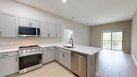 Located at 5790 Stockport St in Riverview, FL, this 2-bedroom, 2-bathroom unit offers a well-designed single-floor layout with a clean, contemporary aesthetic throughout. Light wood-style flooring flows seamlessly across all living areas, complementing the neutral greige wall tones that create a bright, cohesive atmosphere.

The open-concept kitchen and living area serves as the heart of the home. The kitchen is equipped with gray shaker-style cabinetry, white countertops, black hardware accents, and a full suite of stainless steel appliances including a gas range, over-the-range microwave, and refrigerator. The living area benefits from generous natural light and direct access to a private balcony through sliding glass doors, offering pleasant outdoor views.

Both bedrooms are well-proportioned, each featuring natural light from windows with blinds and ceiling fans. The primary bedroom offers comfortable dimensions with its own dedicated bathroom. The primary bath includes a wide vanity with gray cabinetry, white countertop, black fixtures, and a large mirror. The second bathroom features a full tub-shower combination with black hardware accents. A hallway connects the private areas of the unit, and the overall design reflects a modern, move-in-ready finish throughout.