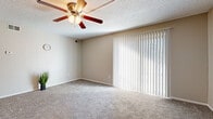 Located at 3801 W 13th St N in Wichita, Kansas, this single-story, 2-bedroom, 1-bathroom residence offers a practical and comfortable layout. The living room serves as the heart of the home, featuring plush carpeting, a ceiling fan with light fixture, and a large sliding glass door dressed with vertical blinds that invite natural light and provide outdoor access. The neutral, warm-toned walls throughout create a cohesive and welcoming atmosphere. The primary bedroom is generously sized, complete with a ceiling fan, a window with blinds, and its own closet. The second bedroom also features carpeted flooring, a window for natural light, and easy access to the shared hallway. The kitchen is equipped with an electric range, overhead exhaust hood, and a refrigerator, set atop tile flooring with ample cabinetry for storage. The bathroom includes a full tub-shower combination with clean white tile surround accented by decorative tile insets. A hallway with two closets provides additional storage throughout. Textured ceilings are consistent across the home, adding a classic touch to this straightforward and functional single-floor layout.