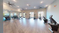 Located at 4035 Flat Shoals Pkwy in Decatur, Georgia, this fitness center offers a generously sized, open-plan workout space spread across a single floor. The interior is bright and welcoming, featuring light wood-look flooring throughout that gives the space a clean, modern aesthetic. Walls are painted in a calming palette of soft blue and neutral tones, complementing the airy atmosphere created by large windows that invite abundant natural light and provide views of the surrounding exterior.

The layout is thoughtfully organized to accommodate a variety of workout styles. Cardio equipment includes multiple treadmills, ellipticals, and stationary bikes — including both upright and recumbent models — while a dedicated free weights area features a full dumbbell rack with an accompanying bench. Large wall mirrors in the free weights section enhance the sense of space and support proper form during exercise.

Overhead, multiple ceiling fans — including an oversized industrial-style fan — ensure comfortable air circulation throughout the workout area. Recessed lighting provides even, well-distributed illumination throughout the space. A restroom is conveniently accessible directly from the fitness floor. The overall design strikes a balance between functionality and comfort, making this a practical and inviting facility for daily exercise.