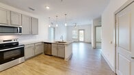 Located at 175 Main Street Market Place SE in Cartersville, Georgia, this single-floor, 2-bedroom, 2-bathroom residence offers a thoughtfully designed layout with contemporary finishes throughout. The open-concept kitchen serves as a focal point, featuring gray shaker-style cabinetry, granite countertops, a large center island with an undermount sink, stainless steel appliances, a tile backsplash, and elegant pendant lighting. Wood-look flooring flows seamlessly through the kitchen and living areas, where a ceiling fan and access to natural light create a bright, welcoming ambiance. Both bedrooms are carpeted and well-lit by windows with blinds that frame outdoor views, and each is equipped with a ceiling fan. The generously sized primary bedroom connects to an en-suite bathroom showcasing granite countertops, gray cabinetry, a tiled soaking tub and shower combination, and wood-look flooring. The second bathroom mirrors this refined aesthetic. Each bedroom is accompanied by a dedicated closet outfitted with wire shelving systems, providing organized and practical storage. The clean, neutral color palette and modern fixtures throughout lend the space a polished, move-in-ready appeal.