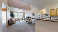 This two-floor residence offers a thoughtfully designed layout with warm, neutral tones and carpeted flooring throughout the main living areas. The open-concept living and dining space is among the home's most notable features, characterized by vaulted ceilings with crown molding, a ceiling fan, and a bank of large windows that flood the room with natural light and provide views of surrounding greenery. A kitchen counter peninsula visually connects the living area to the kitchen, which is appointed with honey-toned wood cabinetry, dark granite-style countertops, tile flooring, and black appliances including a range and built-in microwave.

The bedrooms are carpeted and bathed in natural light from generously sized windows framing tree-lined outdoor views. One bedroom includes direct access to a private balcony, offering an additional connection to the outdoors. A dedicated built-in desk nook with a closet provides a functional workspace. The bathroom features warm wood vanity cabinetry, a white countertop, tile flooring, and a tub-shower combination. Throughout, the space maintains a cohesive, comfortable ambiance with consistent warm neutral walls and practical, well-organized layouts across both floors.