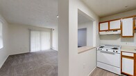 Located at 3801 Memory Lane in Abingdon, Maryland, this single-floor, one-bedroom, one-bathroom residence offers a thoughtfully organized layout that maximizes every square foot. The living room serves as the central gathering space, featuring plush wall-to-wall carpeting, a textured ceiling, and a large sliding glass door dressed with vertical blinds that invites natural light and provides outdoor access. An additional window further brightens the room, creating an open and airy ambiance. The kitchen is positioned adjacent to the living area and features a convenient pass-through window with a breakfast bar ledge, white cabinetry with warm wood accents, and hard-surface flooring. The bedroom is a comfortable, carpeted retreat with a dedicated window offering views of the surrounding community, a textured ceiling, and a closet. The full bathroom is finished with light wood-tone flooring, a full tub-shower combo with safety grab bars, a vanity, and clean white fixtures throughout. A dedicated utility and laundry area houses a stacked washer and dryer unit alongside a water heater, providing excellent in-unit convenience. The overall aesthetic is clean, neutral, and move-in ready.