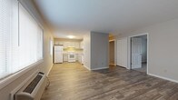 This single-floor unit at 2606 E Edgerton Ave in Cudahy, Wisconsin offers a practical and well-organized layout spread across several connected living spaces. The open-concept living and kitchen area is anchored by durable wood-style vinyl plank flooring, neutral gray walls, and clean white trim, creating a cohesive and low-maintenance aesthetic throughout. A wall-mounted HVAC unit serves the living space, and natural light enters through multiple windows fitted with blinds.

The kitchen is positioned at one end of the open area and features white cabinetry, a white refrigerator, electric range, and dishwasher, along with a double basin sink and ample upper and lower cabinet storage. A center partial wall subtly separates the kitchen zone from the living area without fully enclosing the space.

The bedrooms are carpeted for comfort and are served by baseboard heating. Each room benefits from window natural light, and at least one bedroom includes a built-in closet with a hanging rod. The bathroom is cleanly appointed with a single-sink vanity, mirrored medicine cabinet, toilet, and a full tub and shower unit. Overall, the unit presents a functional and tidy living environment.
