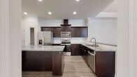 Located at 5223 Hunters Ridge Dr in New Port Richey, Florida, this single-story home offers a thoughtfully designed layout with consistent, modern finishes throughout. The kitchen is a standout feature, showcasing rich dark espresso cabinetry, granite countertops, a central island, a wall-mounted range hood, and a full suite of stainless steel appliances. Light wood-look flooring runs through the main living areas, complementing the neutral wall tones and crown molding that are present throughout the home.

The dining area is defined by an elegant tray ceiling with crown molding detail and a classic chandelier, lending a refined character to the space. An adjacent living area opens seamlessly from the kitchen via a granite-topped breakfast bar, creating a cohesive, open-concept feel. Bedrooms feature plantation shutters and walk-in closets, adding both functionality and charm.

The bathroom includes tile flooring, a granite-topped dark vanity, and a full tub-shower combination with floor-to-ceiling tile surround and brushed nickel fixtures. A dedicated laundry area with tile flooring provides added convenience. The attached garage features an epoxy-coated floor, an automatic opener, and interior access, completing this well-finished home.