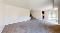 This two-story home in Sacramento, CA offers a practical and comfortable layout across two floors. The main level features a spacious open-plan living and dining area with plush carpeting, textured ceilings, and sliding glass doors that invite natural light and provide outdoor access. A ceiling fan adds functionality to the living space. The kitchen is well-equipped with dark wood cabinetry featuring gold hardware, generous counter space, a peninsula, light wood-style flooring, and white appliances including a refrigerator and electric range with overhead ventilation. A conveniently located half bathroom on the main level includes a vanity with a stone-topped white cabinet and an ornate gold-framed mirror. The staircase with a classic railing leads to the upper floor, where three carpeted bedrooms are situated. The primary bedroom is generously sized and includes a sliding glass door with outdoor views and a closet. Additional bedrooms also feature closets with built-in shelving for organized storage. The full bathroom on the upper level offers a combined tub and shower in a clean white surround. With four closets distributed throughout the home, storage is abundant. The overall aesthetic is neutral and bright, offering a clean canvas throughout.