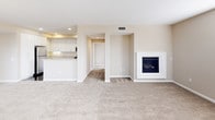 This single-floor residence offers a thoughtfully designed layout that balances comfort and practicality throughout. The kitchen is outfitted with white cabinetry, granite-style countertops, stainless steel appliances including a gas range, over-the-range microwave, and a double-basin sink — providing ample workspace and storage for everyday living. Dark hardwood-style flooring runs through the kitchen and main corridors, creating a clean contrast against the warm, neutral wall tones found throughout the space. The living areas are generously sized and carpeted, with multiple windows along the walls that invite abundant natural light and outdoor views. Bedrooms are carpeted and finished with the same warm neutral palette, offering a calm and restful atmosphere. The primary bathroom is a standout feature, boasting an extended dual-sink vanity with white cabinetry, a large wall mirror with built-in lighting, dark hardwood-style floors, and a separate walk-in shower. A dedicated walk-in closet adjoins the primary suite, offering substantial storage capacity. An in-unit laundry area houses a full-sized side-by-side washer and dryer tucked behind louvered doors with overhead shelving. The overall design is cohesive, practical, and well-suited for comfortable everyday living.