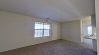 This single-floor residence offers a functional and comfortable layout across one bedroom and two bathrooms. The open living room features plush carpeting, neutral walls, and a large window fitted with blinds that allows ample natural light to fill the space, creating a bright and airy atmosphere. A private entry door is conveniently located within the living area.

The kitchen is designed for efficiency, featuring a galley-style layout with light wood cabinetry, granite-look countertops, tile flooring, a stainless steel sink, and white appliances including a refrigerator, range, microwave, and dishwasher. A pass-through counter with seating connects the kitchen to the living area, enhancing the open feel of the shared space.

The spacious primary bedroom is carpeted and benefits from dual windows that bring in generous natural light, complemented by a ceiling fan for added comfort. It connects conveniently to the hallway leading to the rest of the unit.

Both bathrooms are well-equipped. One features a granite-topped vanity with wood cabinetry and tile flooring, while the other includes a full bathtub with warm-toned tile surround. Clean white finishes and chrome fixtures are consistent throughout both bathrooms, contributing to a cohesive and tidy aesthetic across the entire residence.