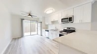 Located at 235 W Orangewood Ave in Anaheim, California, this single-story, 2-bedroom, 1-bathroom home offers a thoughtfully laid-out floor plan designed for comfortable everyday living. The open-concept kitchen and living area serves as the heart of the home, featuring crisp white shaker cabinetry, light quartz countertops, and stainless steel appliances including a gas range, microwave, and dishwasher. A peninsula counter provides additional workspace and casual dining potential. Light wood-style flooring flows throughout the main living areas, enhancing the bright, airy feel of the space. The living room is generously proportioned, bathed in natural light from a large window, and opens via sliding glass doors to a private outdoor patio area. Both bedrooms are carpeted and well-lit with large windows fitted with vertical blinds, offering comfort and privacy. The primary bedroom includes a closet with mirrored sliding doors. The full bathroom is clean and functional, featuring a tub/shower combination, a vanity with quartz countertop, and light wood-style flooring. A textured ceiling and ceiling fan in the kitchen/living area add to the home's practical character. This residence offers a straightforward, move-in-ready layout in a convenient Anaheim location.