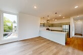 Located at 401 Union Ave SE in Olympia, Washington, this well-designed 2-bedroom, 2-bathroom single-floor residence offers a clean, contemporary aesthetic throughout. Light wood-tone flooring runs continuously across the space, lending a sense of warmth and cohesion.

The open-concept kitchen and living area serves as the heart of the home. The kitchen is outfitted with gray flat-front cabinetry, a wall-mounted range hood, stainless steel appliances including a refrigerator and electric range, and a large white quartz peninsula with an integrated sink. Industrial-style pendant lights add a stylish focal point above the peninsula. The adjacent living area benefits from a large window that invites natural light.

Both bedrooms are generously proportioned and feature large windows with views of the surrounding Olympia neighborhood, light-toned flooring, and closet storage. The primary bedroom is particularly bright, with multiple windows framing views of nearby greenery.

The two bathrooms are clean and functional; one is combined with an in-unit laundry area that includes a front-loading washer alongside a full bathtub and shower. An additional dedicated closet provides supplementary storage. A connecting hallway links the private areas of the home efficiently. The overall ambiance is bright, modern, and move-in ready.
