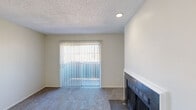 Located at 6424 Iron Horse Blvd in North Richland Hills, TX, this two-bedroom, one-bathroom single-story unit offers a functional and comfortable layout across a well-utilized floor plan. The living room serves as the heart of the home, featuring plush carpet, a tile-surround wood-burning fireplace, and a sliding glass door with vertical blinds that allows natural light to fill the space. Adjacent to the living area, the dining room is finished with wood-look vinyl flooring and a ceiling fan with light fixture, providing a bright and airy atmosphere. The galley-style kitchen is well-appointed with gray cabinetry, white countertops, a mosaic tile backsplash, black appliances including a refrigerator and range, and a stainless steel sink. A dedicated laundry area with washer and dryer hookups is conveniently accessible from the kitchen. The primary bedroom is generously sized, offering carpeted flooring, a walk-in closet with built-in shelving, and a sliding glass door for additional natural light. The second bedroom also features carpet and a standard closet with built-in rod. The bathroom includes wood-look vinyl flooring, a vanity with gray cabinetry, and a shower-tub combo.