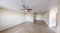 This single-story, 3-bedroom, 2-bathroom home features a practical and cohesive layout designed for comfortable everyday living. The living room serves as a welcoming entry point, complete with a ceiling fan with light fixture, wood-look laminate flooring, and a front door that opens to a bright, open feel. The space flows naturally into the rest of the home via a central hallway. The kitchen is well-appointed with white cabinetry, ample counter space with neutral-toned countertops, a gas range, refrigerator, and double-basin sink — all finished with dark wood-look flooring that adds warmth and contrast. The primary bedroom is a comfortable, well-sized room featuring a ceiling fan, wood-look flooring, and direct access to other areas of the home. The additional two bedrooms each offer wood-look flooring, large windows that bring in natural light and outdoor views, and neutral cream-toned walls. Both bathrooms are cleanly finished, each featuring a full tub-shower combination with white surround panels, a toilet, and wood-look flooring. Throughout the home, consistent warm beige walls, white trim, and wood-look flooring create a unified and neutral aesthetic that is both functional and easy to personalize.