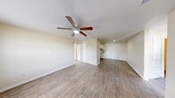 This single-story, 3-bedroom, 2-bathroom home features a practical and cohesive layout designed for comfortable everyday living. The living room serves as a welcoming entry point, complete with a ceiling fan with light fixture, wood-look laminate flooring, and a front door that opens to a bright, open feel. The space flows naturally into the rest of the home via a central hallway. The kitchen is well-appointed with white cabinetry, ample counter space with neutral-toned countertops, a gas range, refrigerator, and double-basin sink — all finished with dark wood-look flooring that adds warmth and contrast. The primary bedroom is a comfortable, well-sized room featuring a ceiling fan, wood-look flooring, and direct access to other areas of the home. The additional two bedrooms each offer wood-look flooring, large windows that bring in natural light and outdoor views, and neutral cream-toned walls. Both bathrooms are cleanly finished, each featuring a full tub-shower combination with white surround panels, a toilet, and wood-look flooring. Throughout the home, consistent warm beige walls, white trim, and wood-look flooring create a unified and neutral aesthetic that is both functional and easy to personalize.
