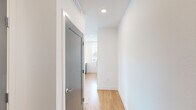 Located at 6609 E Warren Dr. in Denver, CO, this thoughtfully designed one-bedroom, one-bathroom unit offers a clean, modern aesthetic throughout its well-utilized single-floor layout. The open-concept kitchen and living area serves as the heart of the home, featuring light hardwood-style flooring, sleek gray cabinetry with brushed metal hardware, and a tall vertical window that draws in natural light and frames outdoor views. A private entry door with a glass panel further brightens the living space, complemented by recessed lighting overhead. The hallway connecting the main living area to the private quarters is clean and minimal, with a contemporary gray door and recessed ceiling fixtures adding a polished touch. The generously sized bedroom is carpeted for comfort and boasts a large bank of windows with views of the surrounding Denver neighborhood, plus a ceiling fan for year-round climate control. A dedicated walk-in closet off the bedroom provides ample storage with multi-tiered wire shelving and hanging rods. The full bathroom features a tiled tub-shower combo with a curved curtain rod, a white vanity with a light countertop, and warm hardwood-style flooring, completing this well-appointed and move-in-ready Denver residence.