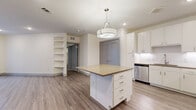 Located in Austin, TX 78757, this thoughtfully designed single-story residence offers 1 bedroom, 2 full bathrooms, and a practical, efficient layout across a comfortable footprint. The open-concept kitchen and living area serves as the heart of the home, anchored by a central island with a warm-toned countertop, crisp white cabinetry, and a suite of stainless steel appliances including a refrigerator with ice maker, range, microwave, and dishwasher. A stylish pendant light fixture overhead adds an elegant focal point to the space. Light wood-style flooring flows consistently throughout, lending warmth and visual continuity. Built-in shelving along the living area wall provides functional display and storage space. The bedroom is a well-sized, airy retreat featuring a ceiling fan, natural light from dual windows with blinds, and direct access to a spacious walk-in closet with multi-level hanging rods and shelving. The two bathrooms are finished with white cabinetry, neutral countertops, large mirrors, and clean tile work, with one featuring a full tub and shower combination. Recessed lighting and a neutral color palette throughout the space create a bright, modern ambiance ideal for comfortable everyday living.