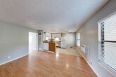 Located at 7323 College View Dr in Rohnert Park, CA, this single-story, one-bedroom, one-bathroom unit offers a practical and well-organized layout. The open-concept main living area seamlessly integrates the living room, dining space, and kitchen into one cohesive zone. The kitchen is outfitted with white cabinetry accented by warm wood trim, granite-style countertops, a built-in sink, a full-size refrigerator, and a range, all set atop light ceramic tile flooring. A ceiling fan overhead serves both the kitchen and adjoining living area, which transitions to smooth hardwood-style flooring. Natural light enters through a window fitted with horizontal blinds, and a wall-mounted HVAC unit provides climate control. The bedroom is a comfortable, private space featuring the same hardwood-style floors, neutral gray walls, a textured ceiling, and a window with outdoor views. Two closets provide generous storage, including a walk-in closet with built-in shelving and hanging rods. The full bathroom includes a vanity with granite-style countertops, warm wood cabinetry, a large mirror, and a shower/tub combination, all finished with clean tile flooring. Textured ceilings throughout add a consistent design element across the unit.