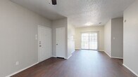This single-story, 2-bedroom, 3-bathroom residence offers a practical and cohesive layout throughout. Rich, dark hardwood-style flooring runs continuously across the main living areas and bedrooms, creating a unified and polished aesthetic. The living room is bright and open, featuring a ceiling fan and a sliding glass door that invites natural light and provides outdoor access. Adjacent to the living area, the kitchen is equipped with white cabinetry, granite-style countertops, black appliances including a refrigerator and electric range, a stainless steel sink, and a convenient peninsula with breakfast bar seating. An open pantry closet provides additional storage directly within the kitchen space. The primary bedroom is comfortably sized, featuring a ceiling fan and a window with natural light. The secondary bedroom also offers ample space with its own window and ceiling fan. Three full bathrooms are present throughout, each featuring granite-style vanity countertops, white cabinetry, and tiled shower-tub combinations. A dedicated laundry area and two closets add to the home's functionality. Textured ceilings are found throughout, and neutral gray wall tones create a clean, move-in ready environment across every room.