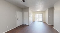 This single-story, 2-bedroom, 3-bathroom residence offers a practical and cohesive layout throughout. Rich, dark hardwood-style flooring runs continuously across the main living areas and bedrooms, creating a unified and polished aesthetic. The living room is bright and open, featuring a ceiling fan and a sliding glass door that invites natural light and provides outdoor access. Adjacent to the living area, the kitchen is equipped with white cabinetry, granite-style countertops, black appliances including a refrigerator and electric range, a stainless steel sink, and a convenient peninsula with breakfast bar seating. An open pantry closet provides additional storage directly within the kitchen space. The primary bedroom is comfortably sized, featuring a ceiling fan and a window with natural light. The secondary bedroom also offers ample space with its own window and ceiling fan. Three full bathrooms are present throughout, each featuring granite-style vanity countertops, white cabinetry, and tiled shower-tub combinations. A dedicated laundry area and two closets add to the home's functionality. Textured ceilings are found throughout, and neutral gray wall tones create a clean, move-in ready environment across every room.