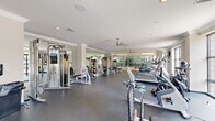 Located at 45 Creekside Ln in Malvern, PA, this professionally outfitted fitness center offers a spacious, single-floor layout designed to support a comprehensive workout experience. The facility is thoughtfully organized into distinct functional zones, making efficient use of its generous floor area.

The main exercise floor features durable rubber flooring and hosts an extensive array of cardio equipment, including treadmills, elliptical trainers, stationary bikes, and rowing machines. A dedicated strength training section is equipped with cable machines, weight benches, and free weights to accommodate a full range of resistance exercises.

A standout architectural feature is the full-height glass partition wall that separates a hardwood-floored studio space, ideal for stretching, yoga, or group fitness activities. Floor-to-ceiling windows line the perimeter, flooding the interior with natural light and offering views of the surrounding greenery.

The space is finished with crown molding, recessed lighting, and ceiling fans that contribute to a clean, polished aesthetic. Large wall-mounted mirrors amplify the sense of openness throughout. The bright, neutral color palette and well-maintained equipment create a welcoming and motivating environment suited for a wide range of fitness routines.