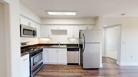 This 2-bedroom, 2-bathroom residence on Magnolia Blvd in Burbank, CA offers a well-organized single-floor layout with a clean, modern aesthetic throughout. The open living and dining area features warm hardwood-style flooring, a ceiling fan with integrated lighting, and track lighting along the ceiling, creating a bright and functional space. The kitchen is outfitted with white shaker cabinetry, dark granite countertops, a skylight panel for added brightness, and a full suite of stainless steel appliances including a gas range, dishwasher, microwave, and refrigerator. A sliding glass door leads from the living area to a private balcony offering views of surrounding palm trees and greenery. Both bedrooms are carpeted and include ceiling fans and ample closet space — the primary bedroom features a mirrored sliding-door closet with built-in shelving. The two bathrooms include hardwood-style flooring, white vanity cabinetry, and stone-accented countertops; one bathroom includes a full tub-shower combination. Additional highlights include in-unit laundry, multiple hallway closets for storage, and a neutral color palette throughout that enhances the sense of light and space.