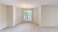 Located at 4550 47th St W in Bradenton, FL, this one-bedroom, one-bathroom unit offers a thoughtfully organized single-floor layout. The kitchen is well-appointed with white cabinetry, granite-style countertops, stainless steel appliances including a range, dishwasher, and refrigerator, and durable wood-look flooring. A peninsula counter connects the kitchen to the adjacent dining area, creating an efficient, open flow between the two spaces. The dining area features soft carpeting, neutral beige walls, and a chandelier light fixture, with a window that brings in natural light and views of surrounding greenery. The living and dining spaces maintain a cohesive, airy feel throughout. The bedroom is a comfortable size, finished with plush carpet, a ceiling fan, and access to a dedicated walk-in closet with built-in shelving. The full bathroom includes a single-sink vanity with granite-style countertops, white cabinetry, a large mirror with overhead globe lighting, and a shower/tub combination. Textured ceilings are consistent throughout the unit. The overall design is clean and functional, with a warm, neutral color palette that lends itself well to a variety of furnishing styles.